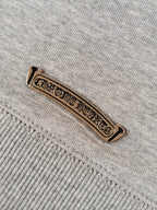 Light gray hoodie with gold-tone logo label on seam