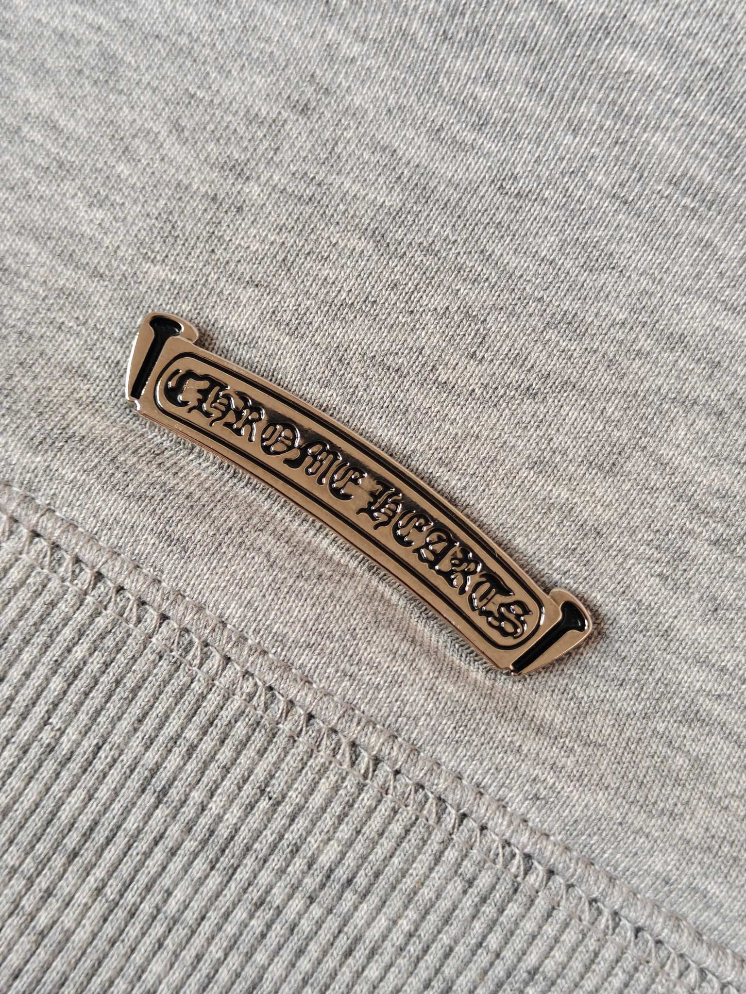 Light gray hoodie with gold-tone logo label on seam