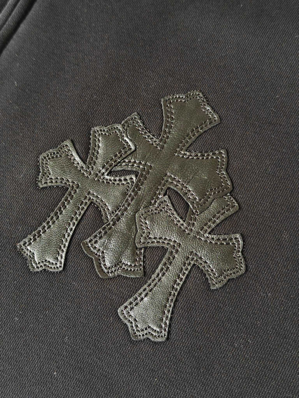 Embroidered cross appliques on dark hoodie fabric