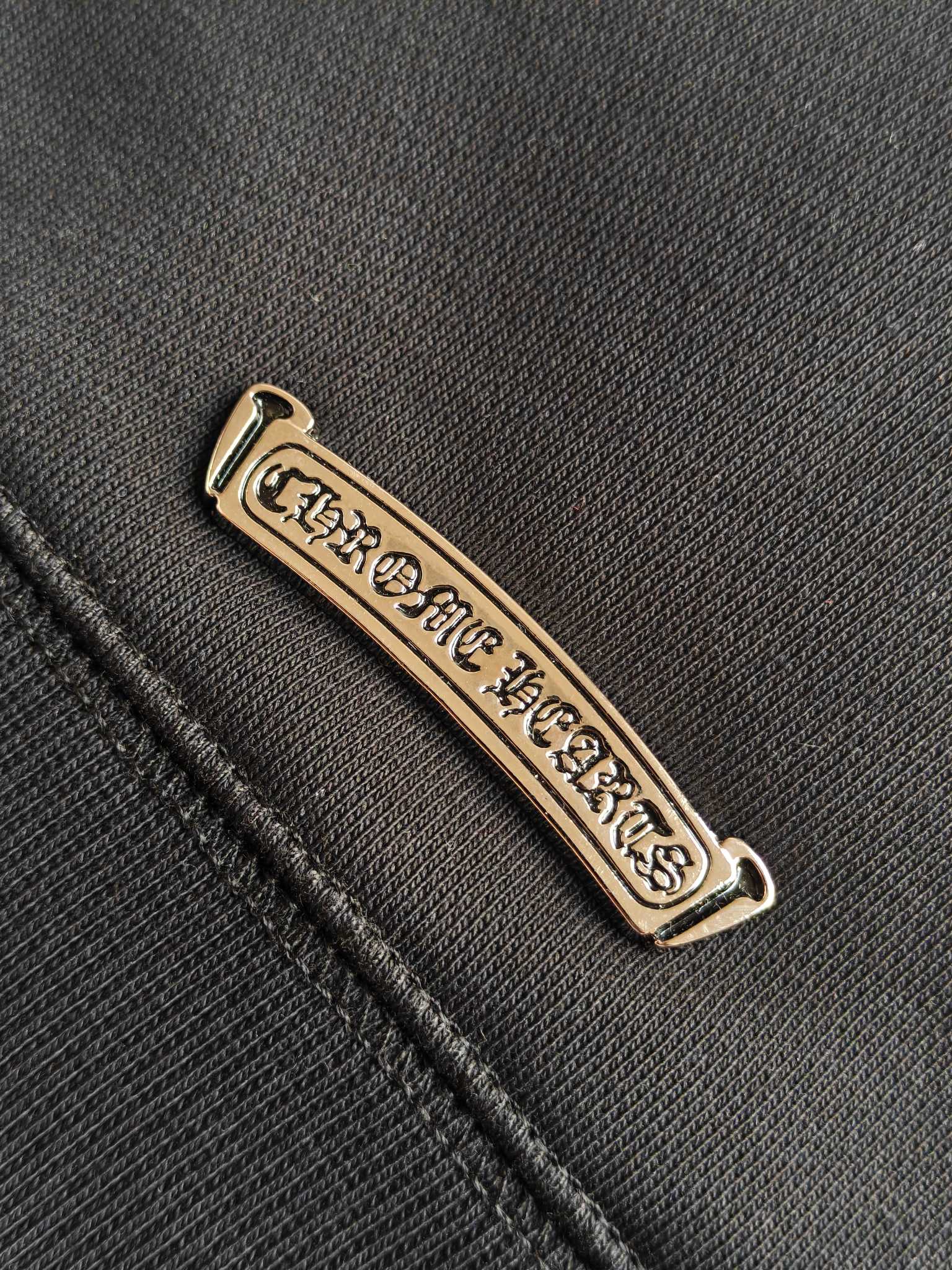 Metal logo label on dark hoodie fabric