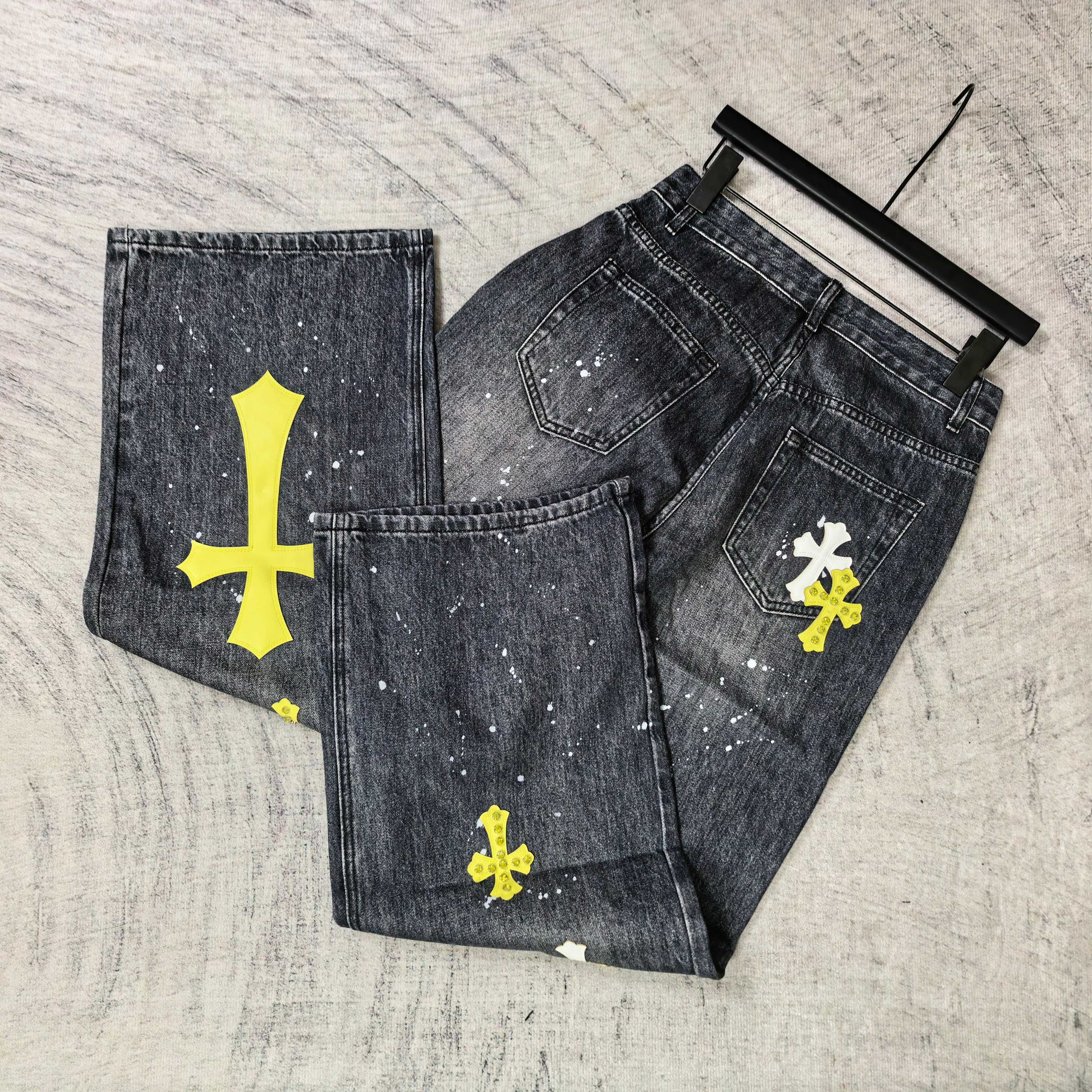 Set of dark denim pants with yellow cross prints and white speckled paint