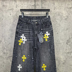 Dark denim pants with large cross prints, including yellow and white on legs