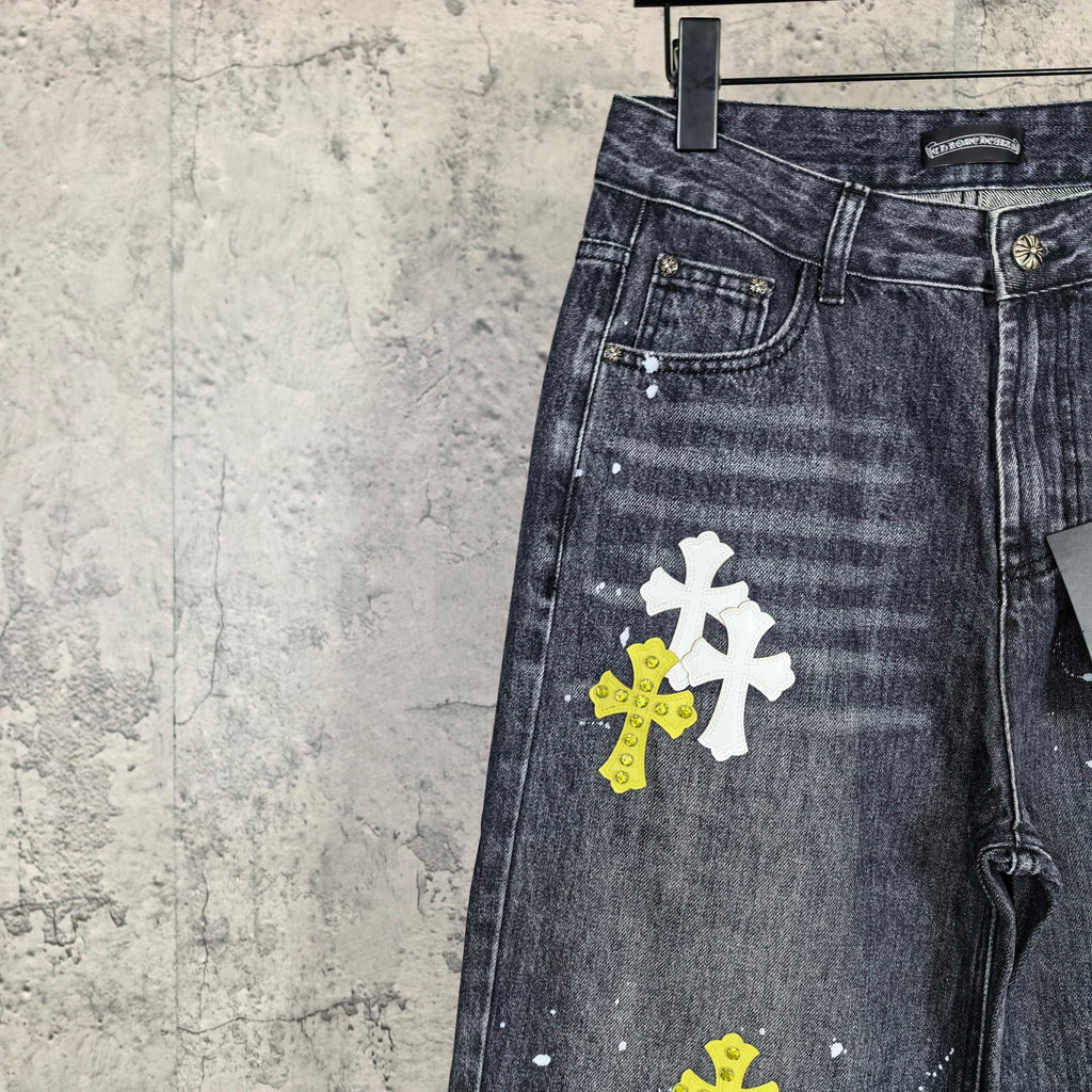 Dark denim pants close-up of pocket area with stacked yellow and white cross graphics