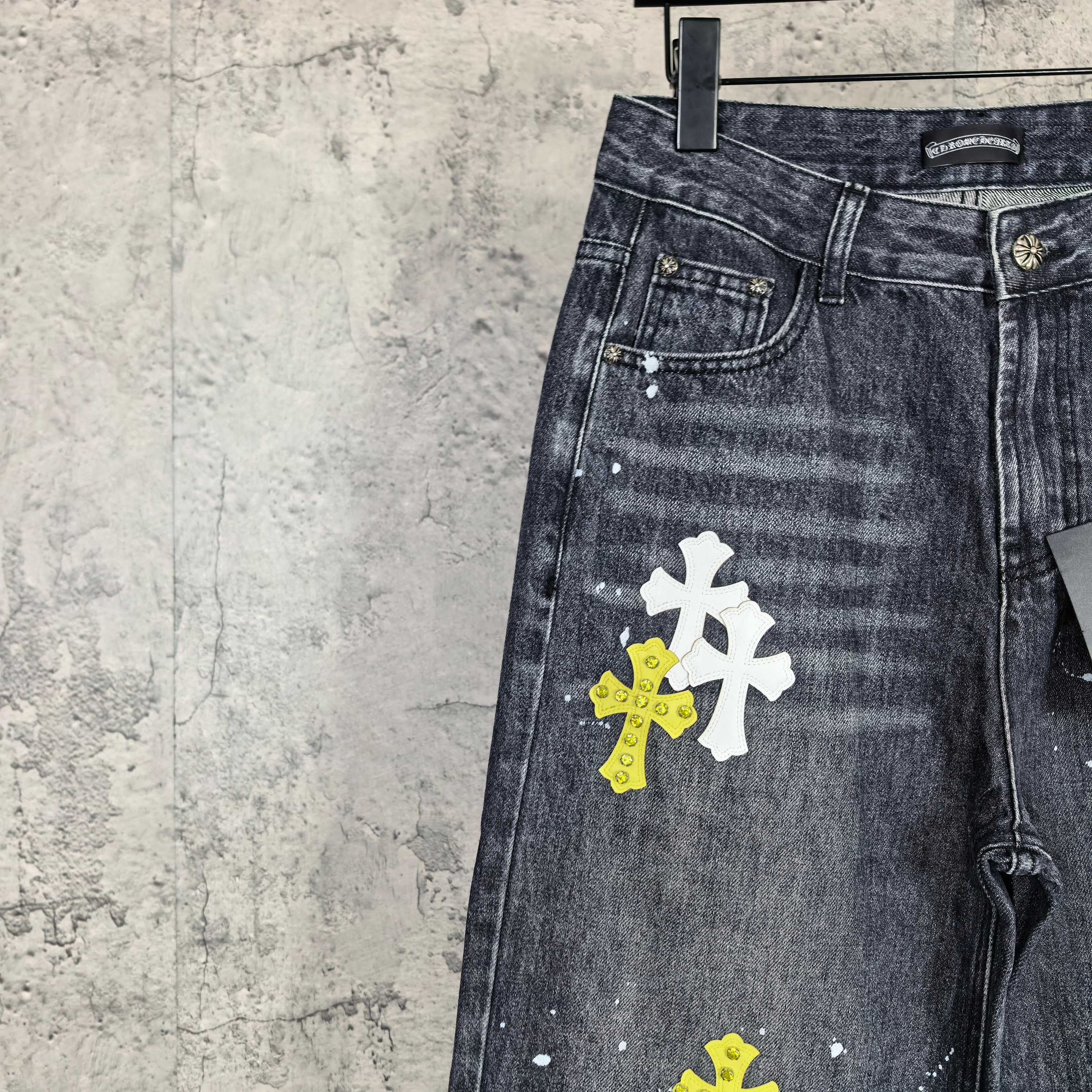 Dark denim pants close-up of pocket area with stacked yellow and white cross graphics