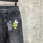 Dark denim pants close-up with pocket and cross graphic plus key-shaped tag print