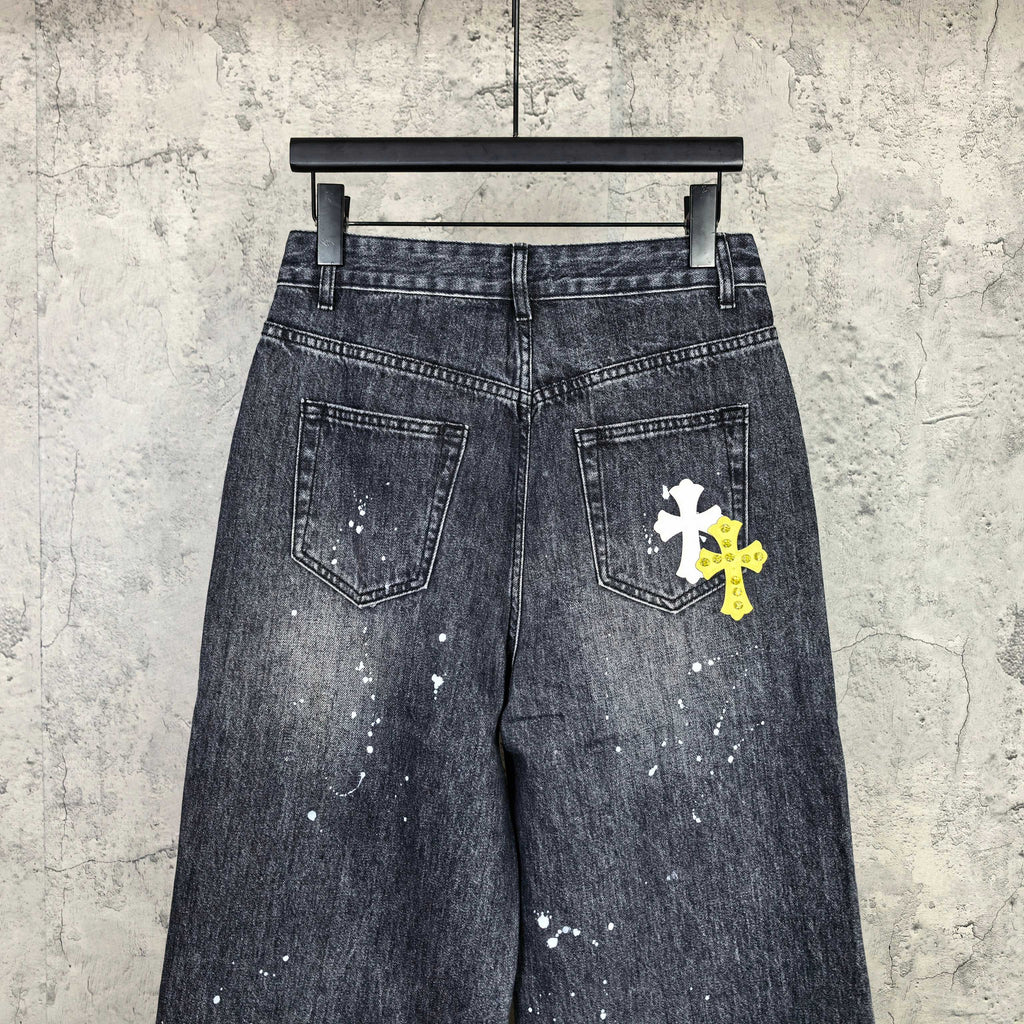 Dark denim pants with two front pockets and a white cross patch on right leg