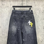 Dark denim pants with two front pockets and a white cross patch on right leg