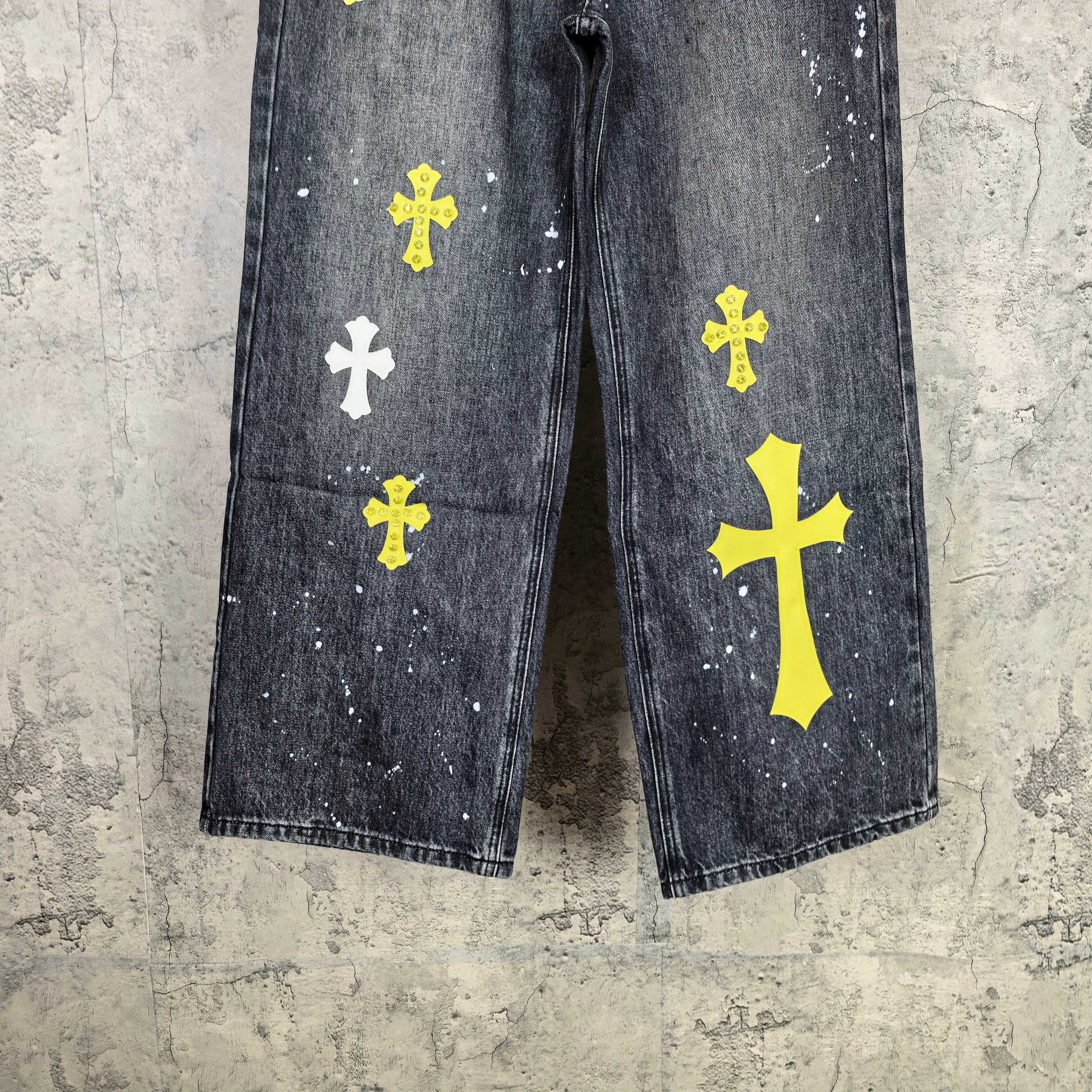 Dark denim pants front view with yellow and white cross prints on both legs