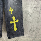 Dark denim pants with large yellow cross patch and white speckles