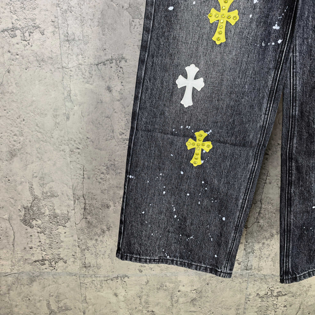 Dark denim pants with yellow and white cross graphics across leg