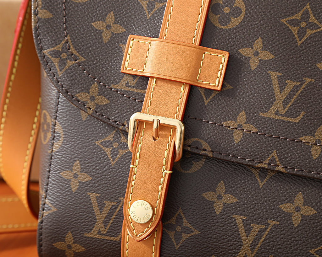 Monogram crossbody bag buckle and tan leather strap closure detail