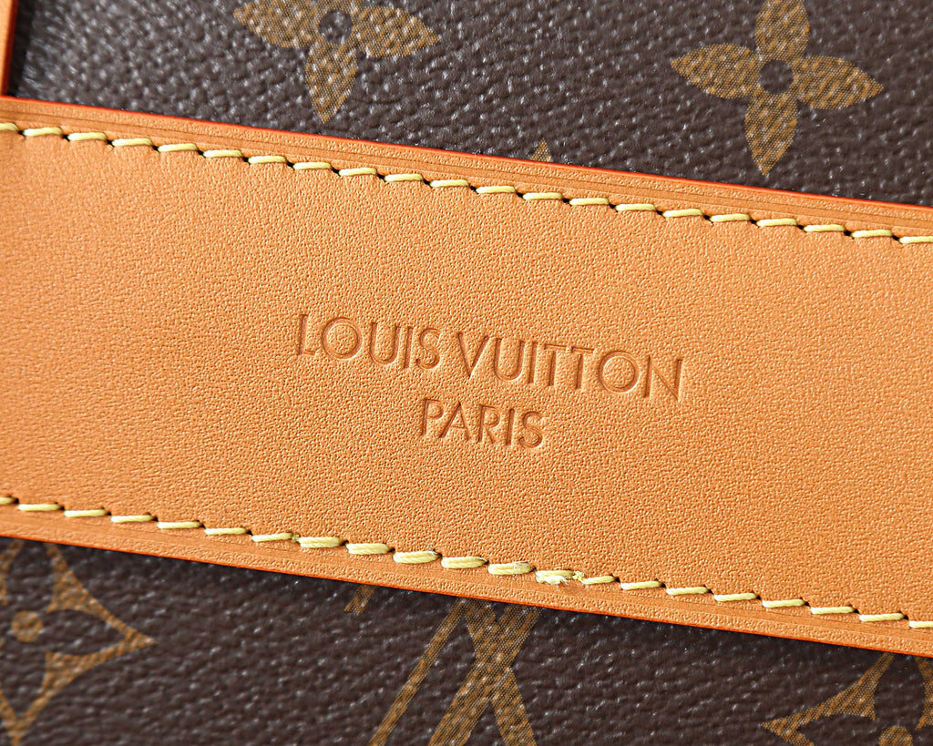 Leather logo patch with stitched trim on monogram crossbody bag edge