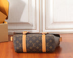 Monogram crossbody bag with tan center strap and gold-tone buckles