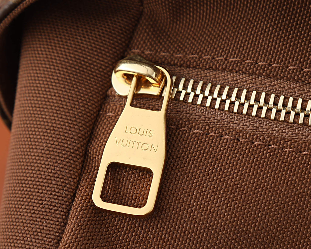 Gold-tone zipper pull on monogram crossbody bag with fabric texture