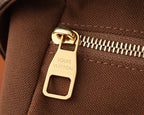 Gold-tone zipper pull on monogram crossbody bag with fabric texture