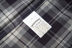 Long plaid fabric garment with stitched hem and care label