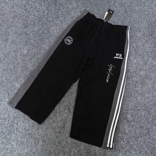 Black track pants with white side stripes, elastic waist, Y-3 logo and graphic print