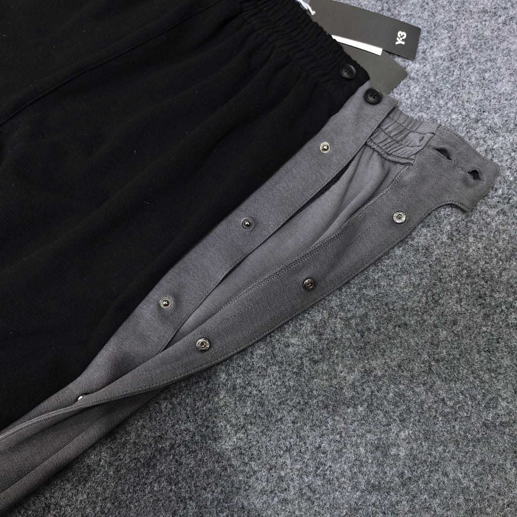 Black and gray track pants with snap-button side panels and elastic waistband