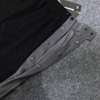 Black and gray track pants with snap-button side panels and elastic waistband