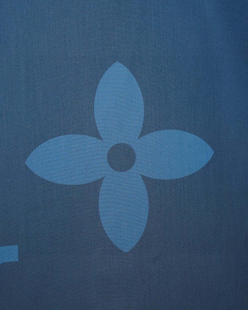 Bright blue short-sleeve shirt detail with flower-like tonal monogram motif