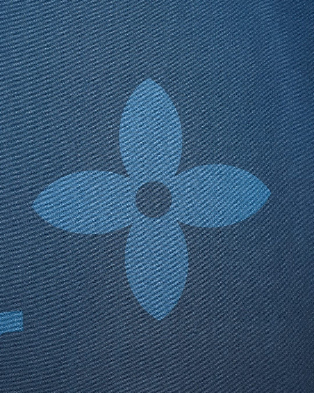 Bright blue short-sleeve shirt detail with flower-like tonal monogram motif