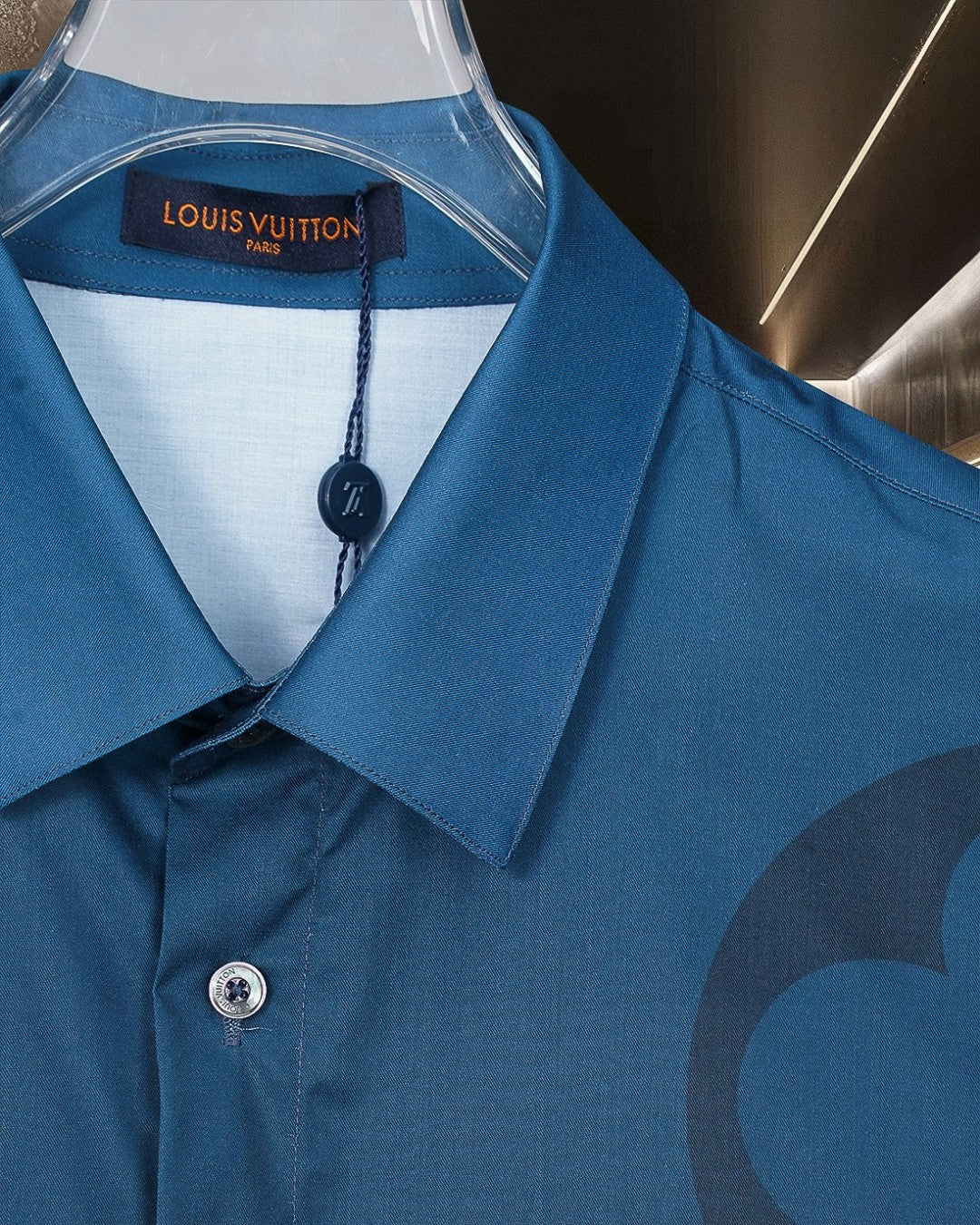 Close-up of bright blue short-sleeve shirt collar with button and neck logo label