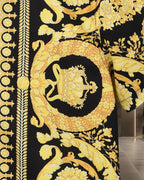 Versace short-sleeve shirt fabric close-up in black with gold crest and leaf pattern