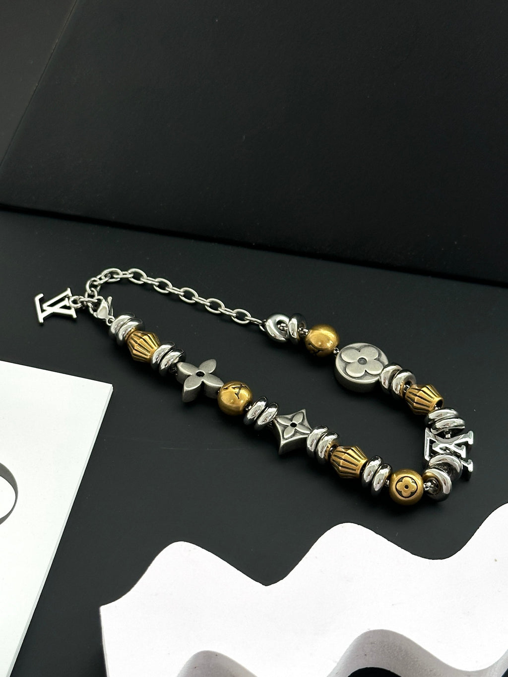 Silver and gold beaded charm bracelets with chain links on a dark background