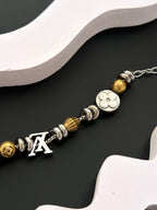 Close-up of gold and silver beaded charm bracelet with clasp and Louis-style charms