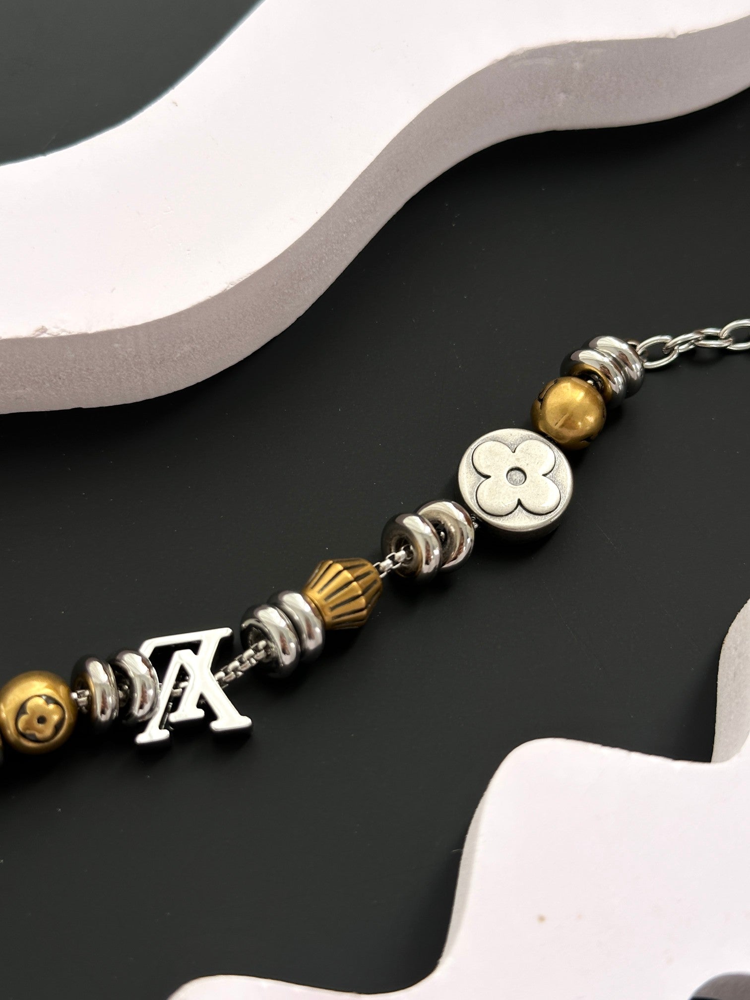 Close-up of gold and silver beaded charm bracelet with clasp and Louis-style charms