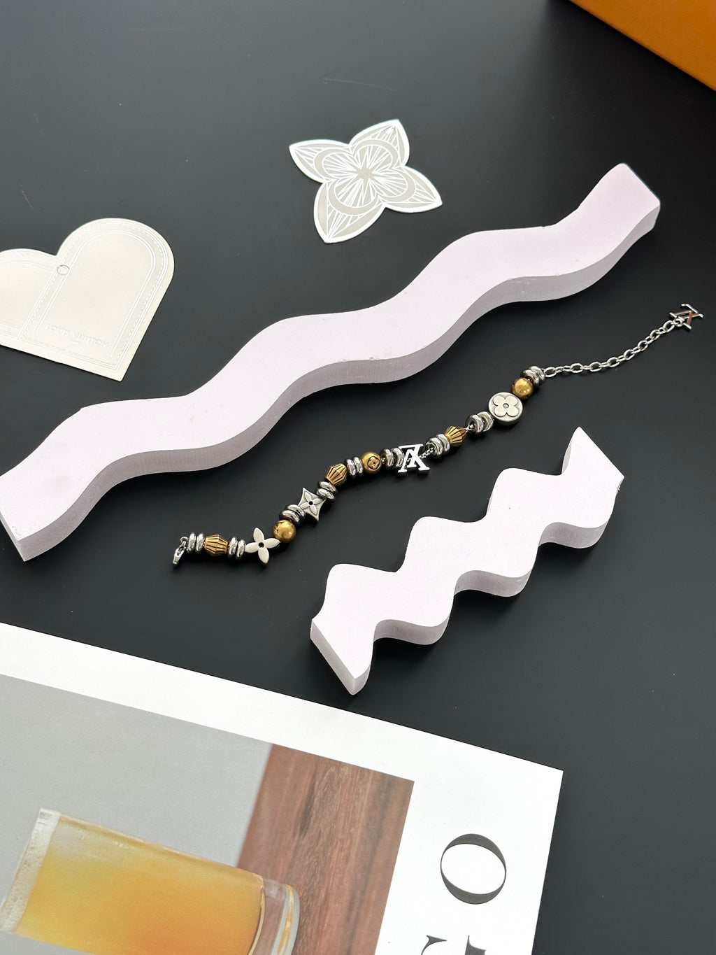 Gold and silver beaded charm bracelet set on white display stand