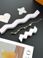 Gold and silver beaded charm bracelet set on white display stand