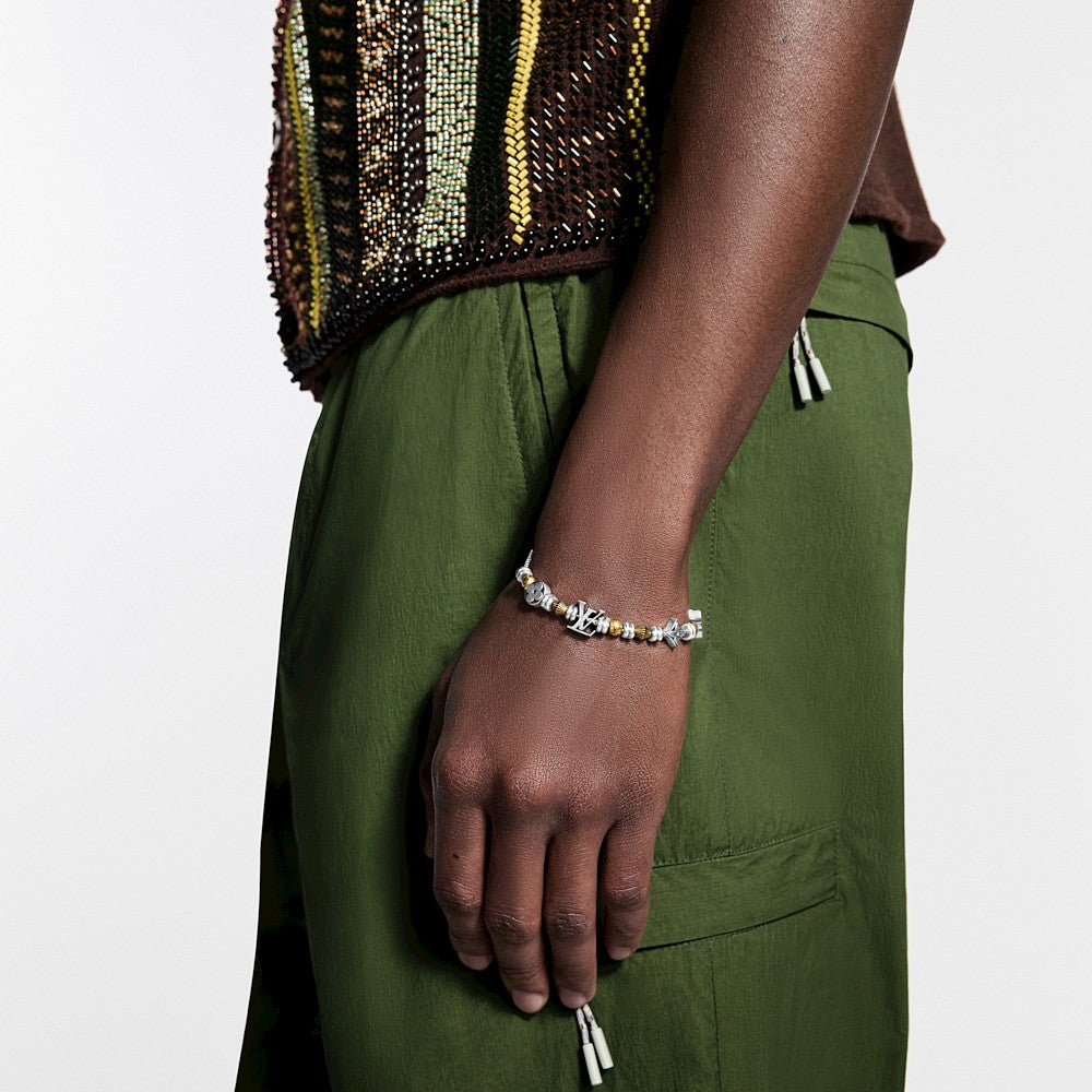 Person wearing a gold and silver beaded bracelet on the wrist