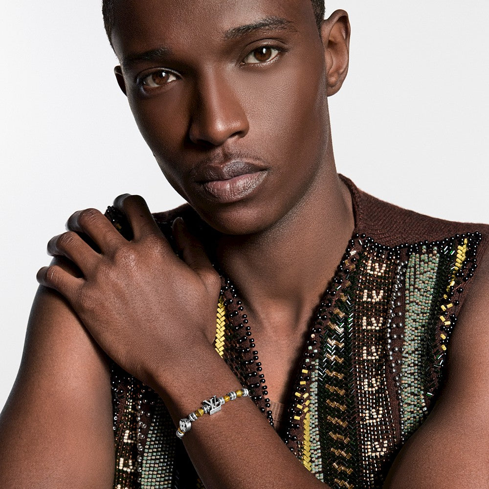 Person wearing layered gold and silver beaded bracelets and a necklace