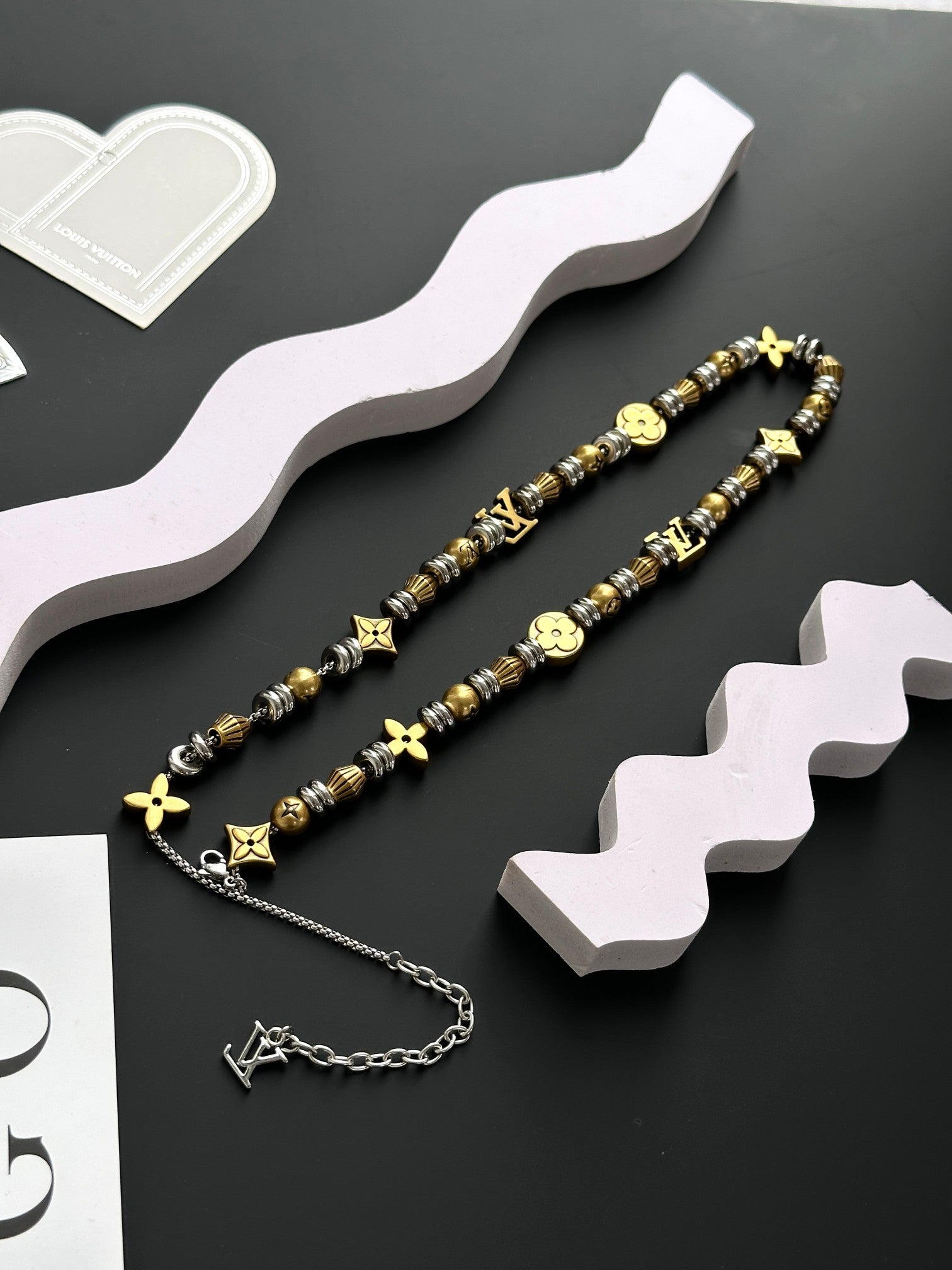 Louis Vuitton beaded necklace set with gold cross and star charms laid out