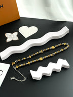 Louis Vuitton beaded necklace pair with gold and silver charms on a white base