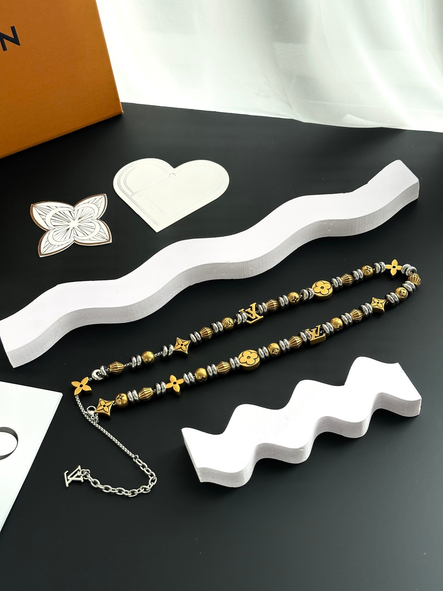 Louis Vuitton beaded necklace pair with gold and silver charms on a white base