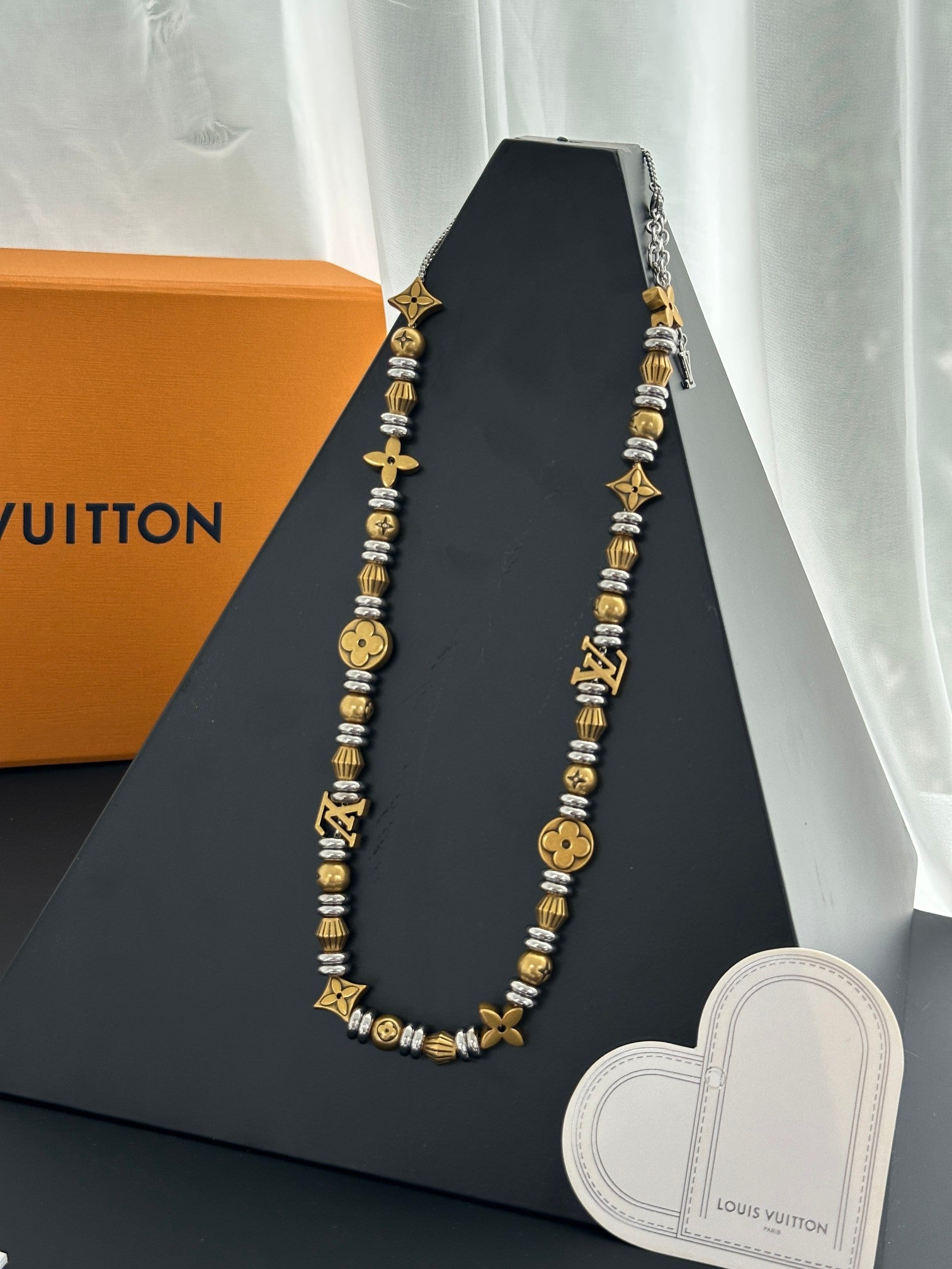 Louis Vuitton beaded necklace on a display stand with heart-shaped charm card