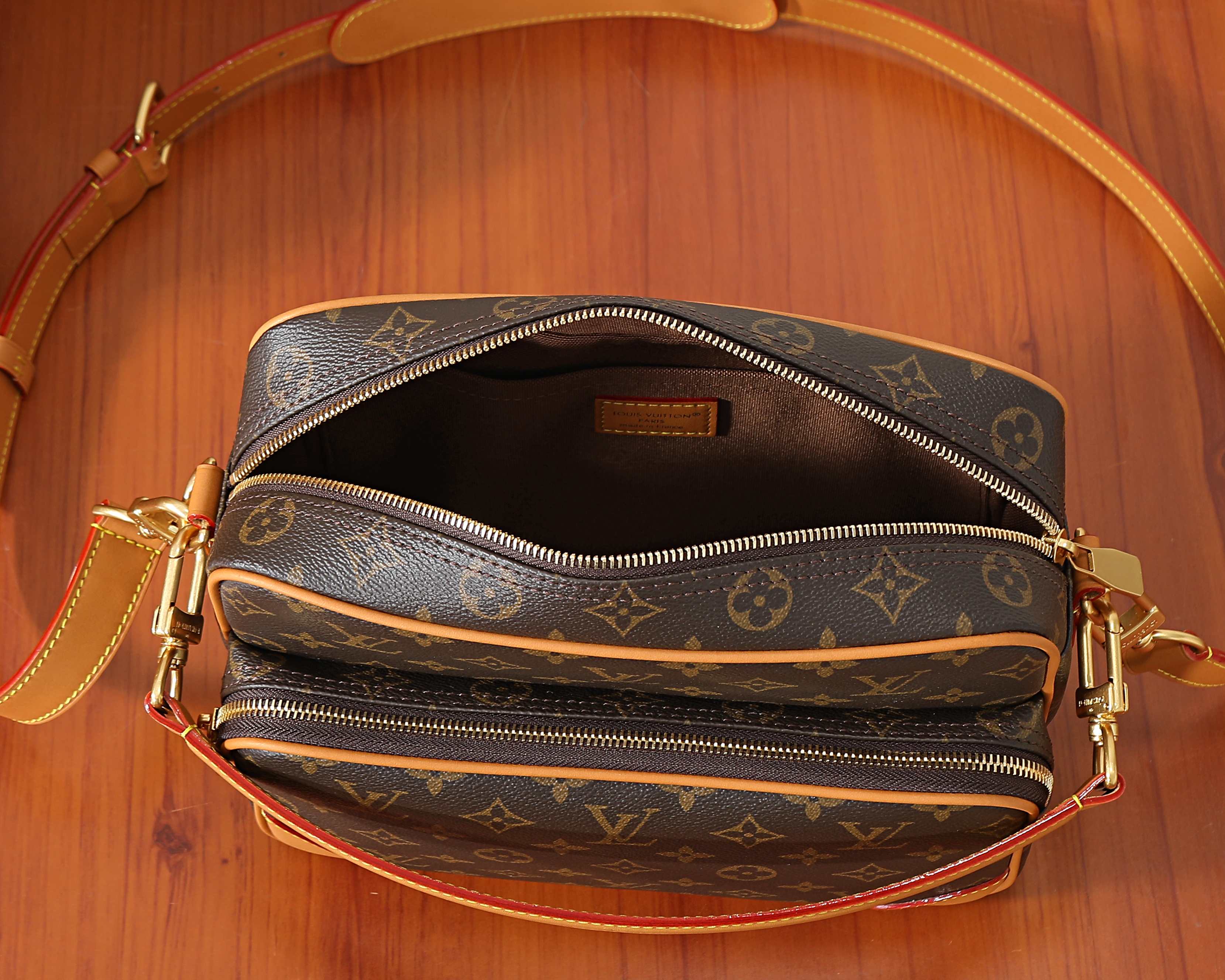 Monogram crossbody bag interior view with two zip compartments and tan lining