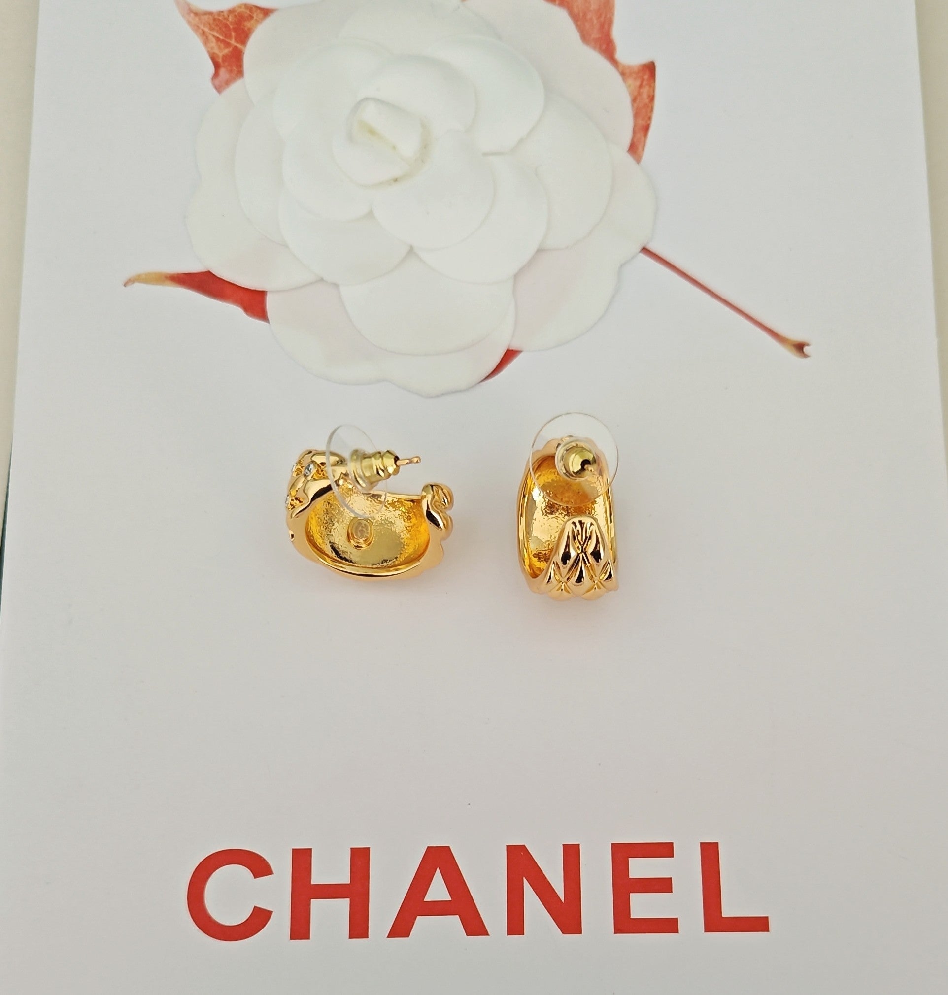 Gold-tone earrings with crystal-like details, shown as a pair