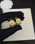 Gold-tone hoop earrings with crystal-like details, paired on dark pouch