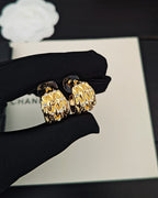Gold-tone hoop earrings with crystal-like details, paired on dark pouch
