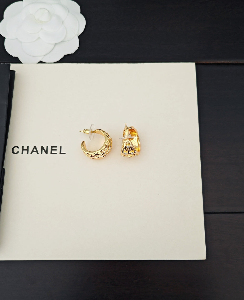 Gold-tone hoop and stud earrings with crystal-like details on white card