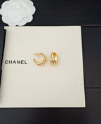 Gold-tone hoop and stud earrings with crystal-like details on white card