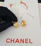 Gold-tone hoop earrings with crystal-like details on white presentation card