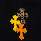 Close-up of orange and yellow cross embroidery on black denim fabric