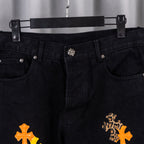 Front view of black denim pants with metal button closure and cross embroidery