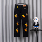 Black denim pants with scattered orange and yellow cross embroidery and logo patch