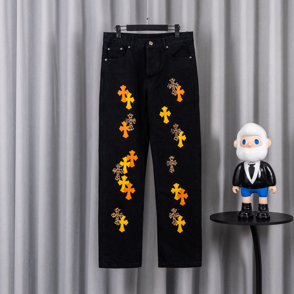 Black denim pants with orange and yellow cross embroidery on the legs