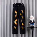 Black denim pants with orange and yellow cross embroidery on the legs